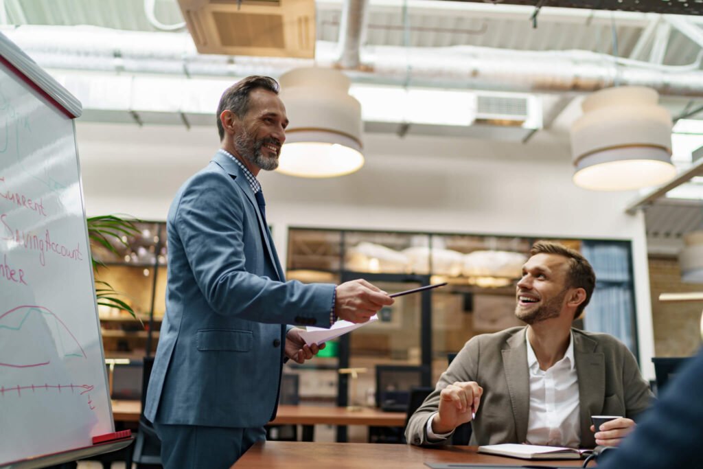 mature-business-coach-or-speaker-make-flip-chart-presentation-to-diverse-businesspeople-at-meeting.jpg
